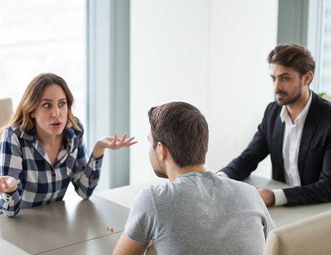 Unhappy young couple at meeting with lawyer about divorce